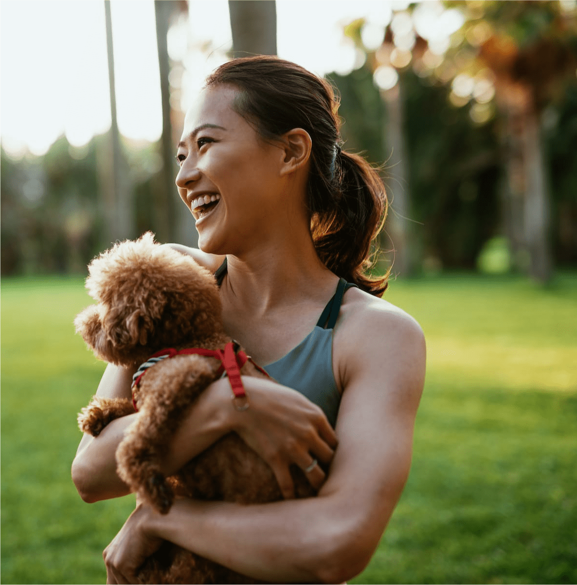 woman laughing with her puppy at the park