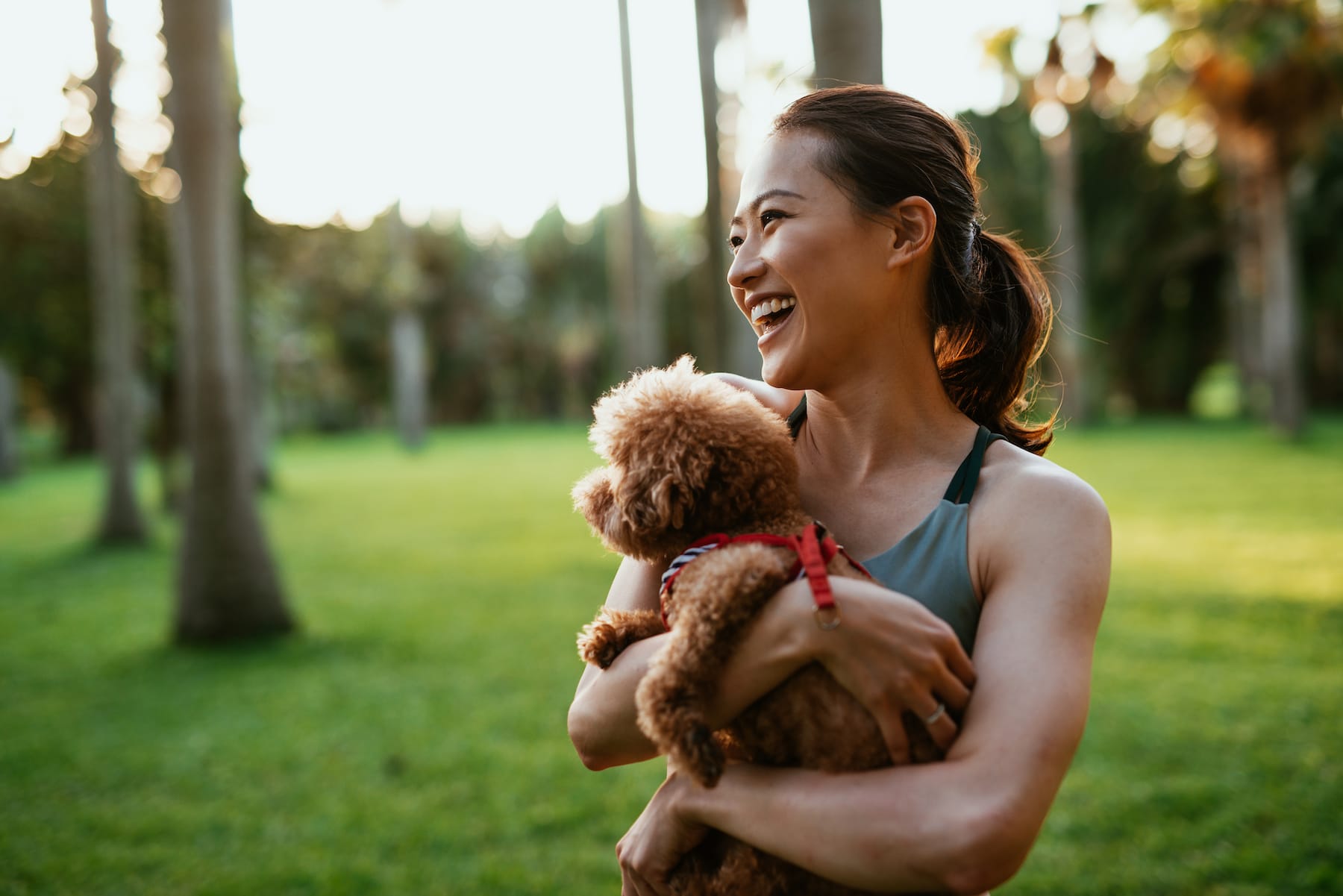 woman laughing with her puppy at the park